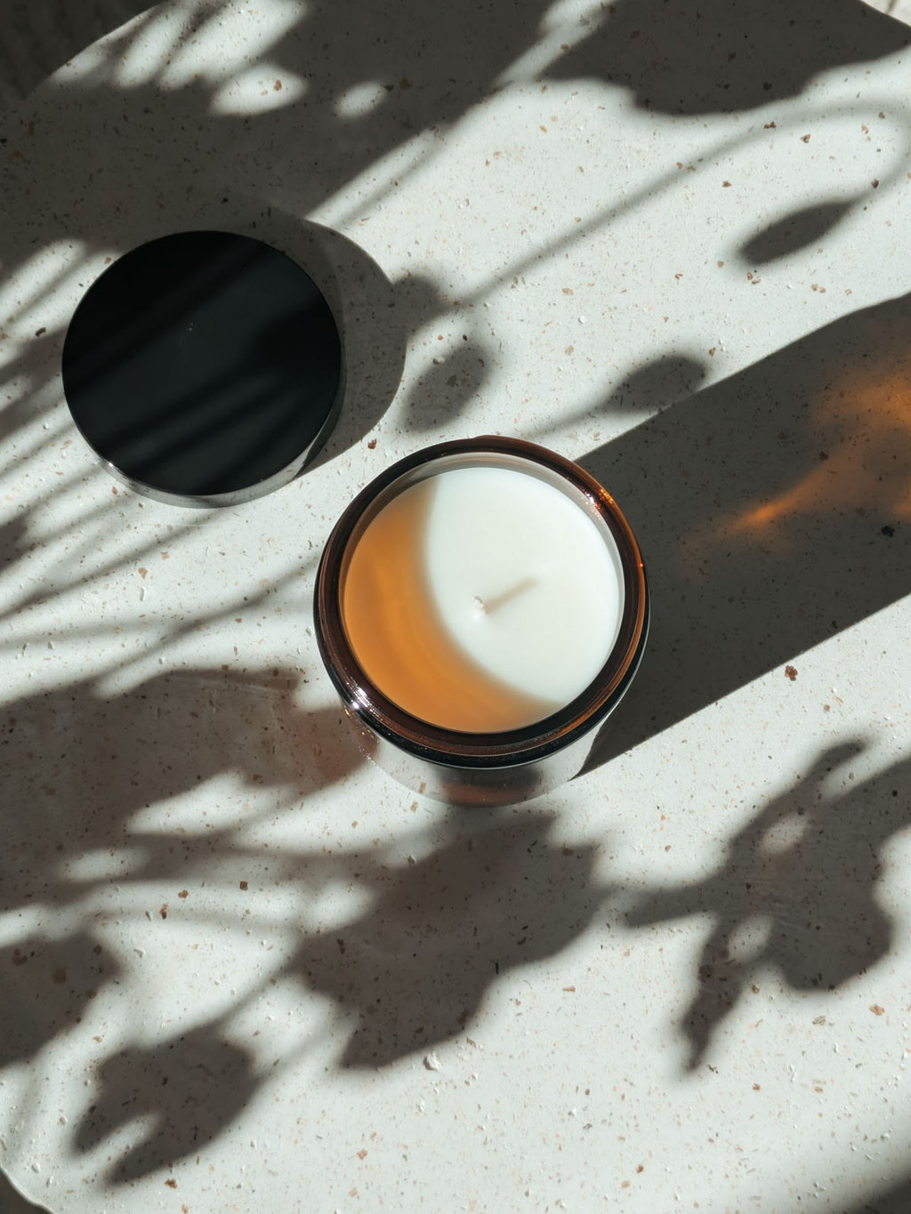 Sandalwood and Cedarwood candle, open jar with lid beside, top-down dappled light